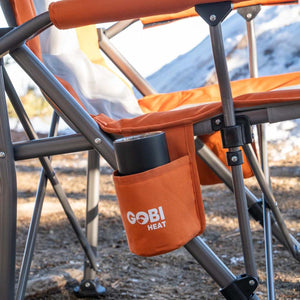 Black tumbler in the cup holder of an orange Gobi Heat folding camping chair