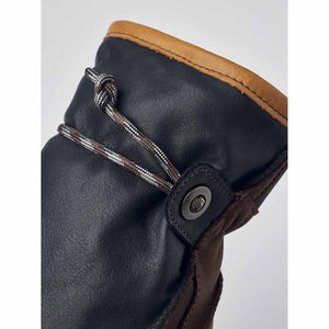 Close up of black leather glove cuff with tan trim and patterned drawstring cord