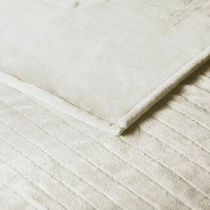 Close up of cream colored velvet blanket with vertical channel stitching