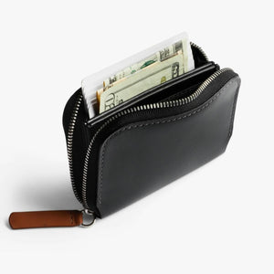 Bellroy black leather zippered wallet containing cards and US currency