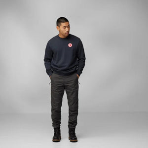 Man wearing a navy FjallRaven sweatshirt and dark trousers