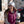 Woman wearing a white beanie and a maroon Venture Heat vest sitting at an outdoor table with a coffee cup