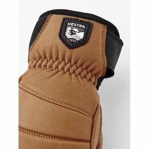 Tan leather Hestra glove with black trim and brand logo patch