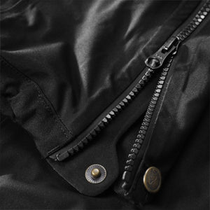 Close up of black fabric with a heavy duty zipper and metal snap button