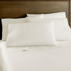 White bed sheets and pillowcases on a bed with a wooden headboard