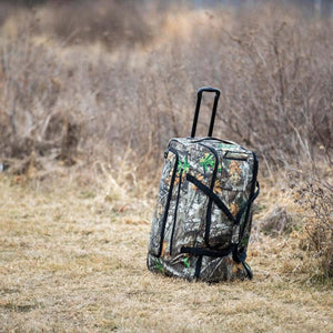 DSG Outerwear rolling gear bag in camouflage print standing in a field