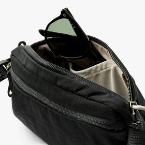 Black Bellroy crossbody bag with sunglasses stored in the open main compartment