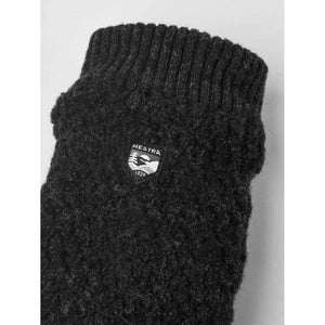 Close up of black Hestra wool glove with brand logo patch