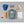 FjallRaven Kanken backpack with cap, Primus bottle, markers, notebook, apple, banana, and nuts on grey background