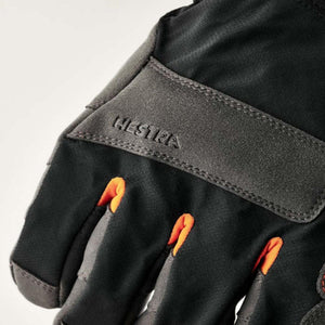 Close up of black Hestra glove with grey trim and orange finger accents