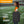 Person carrying a black portable stadium seat with a handle on a football field