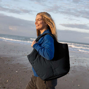 Person carrying a black Got Bag tote on the beach