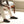 Person wearing Acorn dark grey wool slippers while sitting on a wooden bench