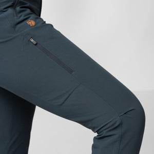 Close up of dark blue Fjallraven trousers featuring a zippered thigh pocket and leather fox logo