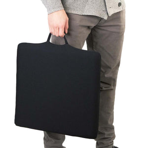 Person holding a square black seat cushion with a carry handle