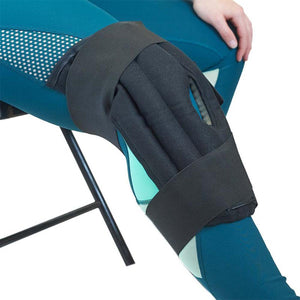 Black knee ice wrap secured with straps on a person wearing teal leggings