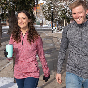 Man and woman walking on a snowy sidewalk wearing quarter zip pullovers