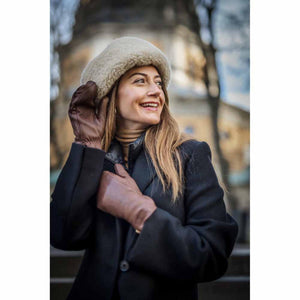 Woman wearing Hestra brown leather gloves and a beige shearling hat