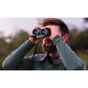 Man with beard using green binoculars outdoors