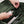 Person placing a white power adapter into an interior pocket of an olive green backpack