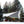 Snow Peak tarp set up over a table and chairs in a snowy forest with a campfire
