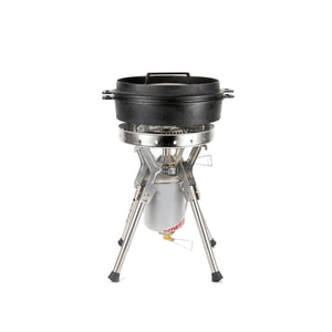 Cast iron dutch oven sitting on a portable camping stove with a fuel canister