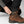 Hand adjusting the snap button strap on the hem of black FjallRaven trousers over a brown Hanwag hiking boot