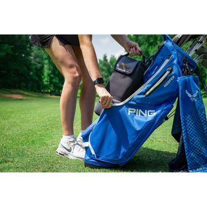 Person placing a black Kanga Coolers beverage cooler into a blue Ping golf bag on a golf course