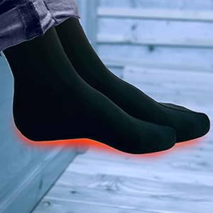 Person wearing black heated socks with glowing red heating elements on the soles