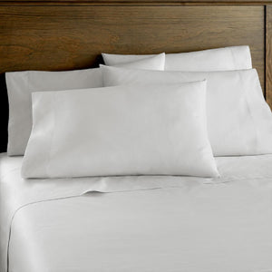 Shavel white bed sheet set with pillows on a wooden headboard