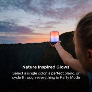 Person holding a glowing BioLite lantern against a sunset landscape