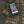 Smartphone displaying Volt Clothing app interface resting on a black quilted heated jacket