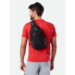 Man wearing a black Nathan sling backpack over a red t-shirt