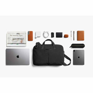 Bellroy black briefcase surrounded by laptop tablet phone charger pens and personal accessories