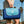 Person carrying a folded blue CGEAR sand-free mat with a light blue flap and logo