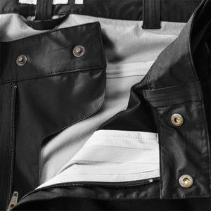 Close up of black trousers showing metal snap buttons and zipper detail