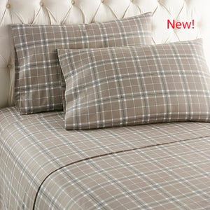 Shavel tan plaid bed sheet set with two pillows on a tufted headboard