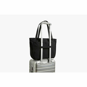 Black Bellroy tote bag attached to a silver rolling suitcase handle