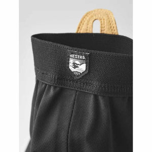 Black Hestra glove cuff with branded logo patch and tan pull tab