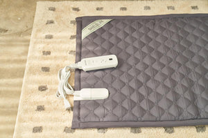 ShieldLife grey quilted heating mat with white power controller on a patterned rug