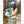 Woman wearing a light blue bucket hat and vest over a green top and striped skirt in a forest setting
