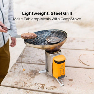Person using a spatula to flip a burger patty on a BioLite CampStove steel grill attachment