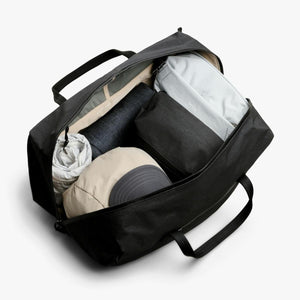 Open black Bellroy duffel bag packed with clothing and accessories
