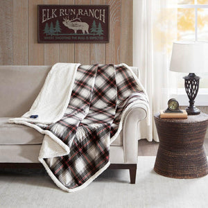 Woolrich plaid heated throw blanket draped over a beige sofa