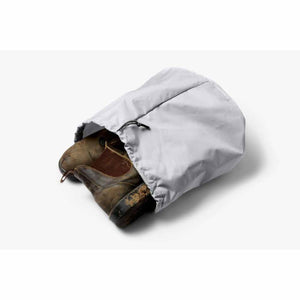 Bellroy light grey drawstring shoe bag containing a pair of muddy brown leather boots