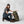 Woman wearing FjallRaven cap and hiking gear kneeling beside an olive green backpack