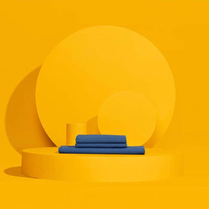 Folded blue Outlast bedding set on a yellow circular platform