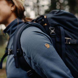 Person wearing a blue FjallRaven fleece with a FjallRaven logo patch and a backpack