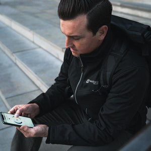 Man wearing a Venture Heat jacket using a smartphone app to control temperature settings