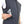 Person placing a smartphone into the zippered chest pocket of a grey athletic vest